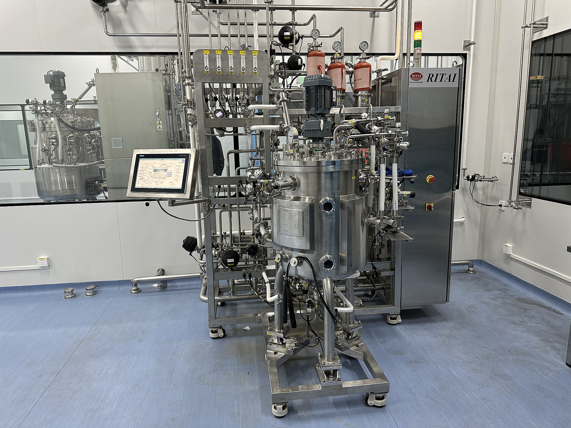 Stainless steel bioreactor fermenter with control panel in a biomanufacturing cleanroom
