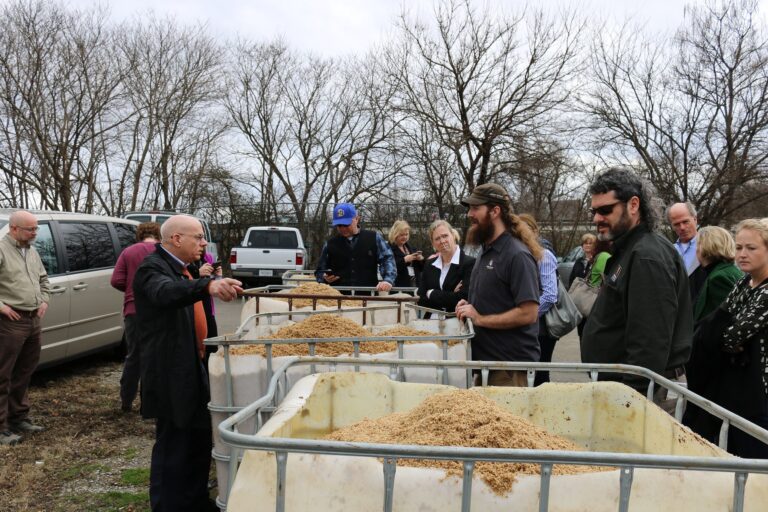 Brewers and regulators inspecting totes of spent grain at a brewery