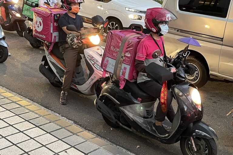 foodpanda delivery riders on scooters waiting at a traffic light in Taipei