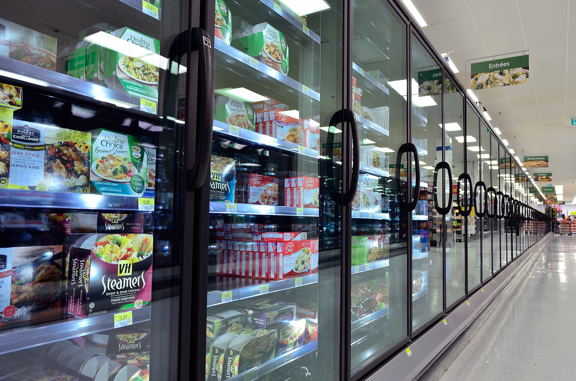 Supermarket frozen food aisle with glass-door freezers stocked with packaged frozen meals