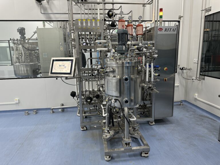 Stainless steel pilot-scale bioreactor with control touchscreen and process piping in a fermentation laboratory