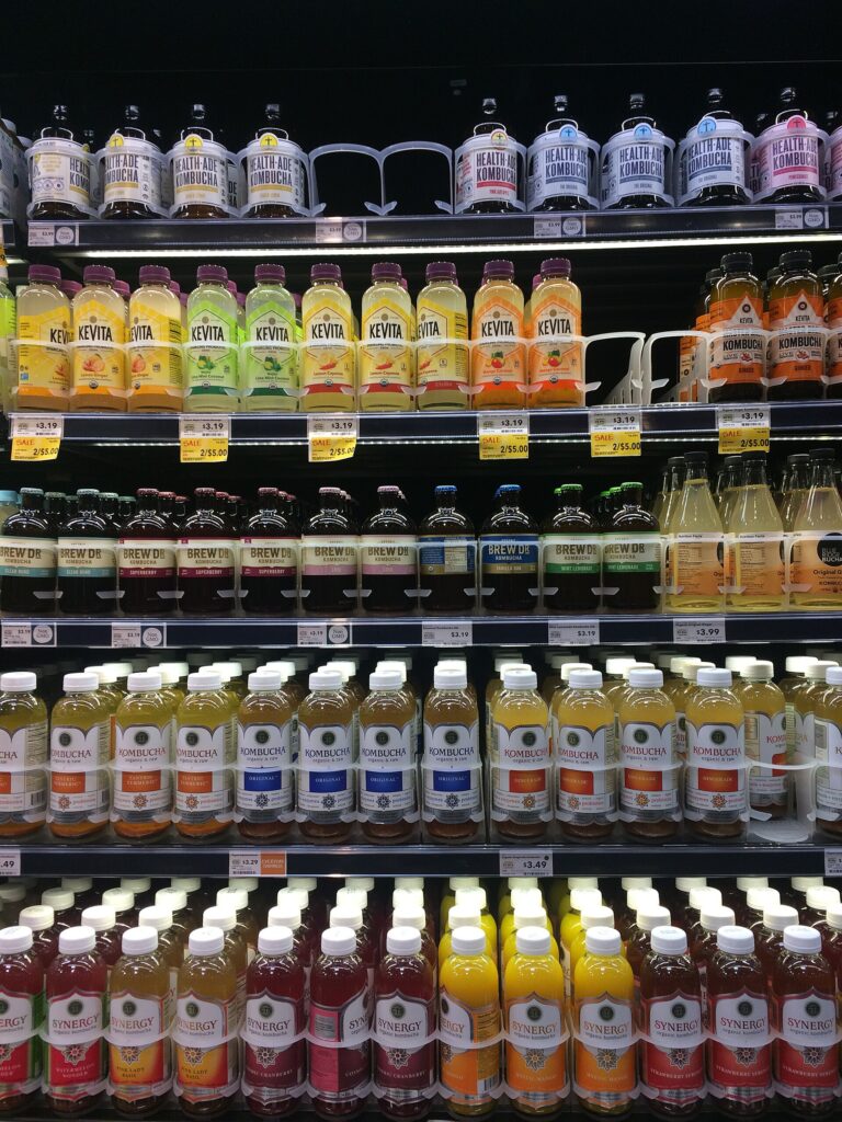 Refrigerated store shelves stocked with bottled kombucha and functional drinks from consumer packaged goods brands
