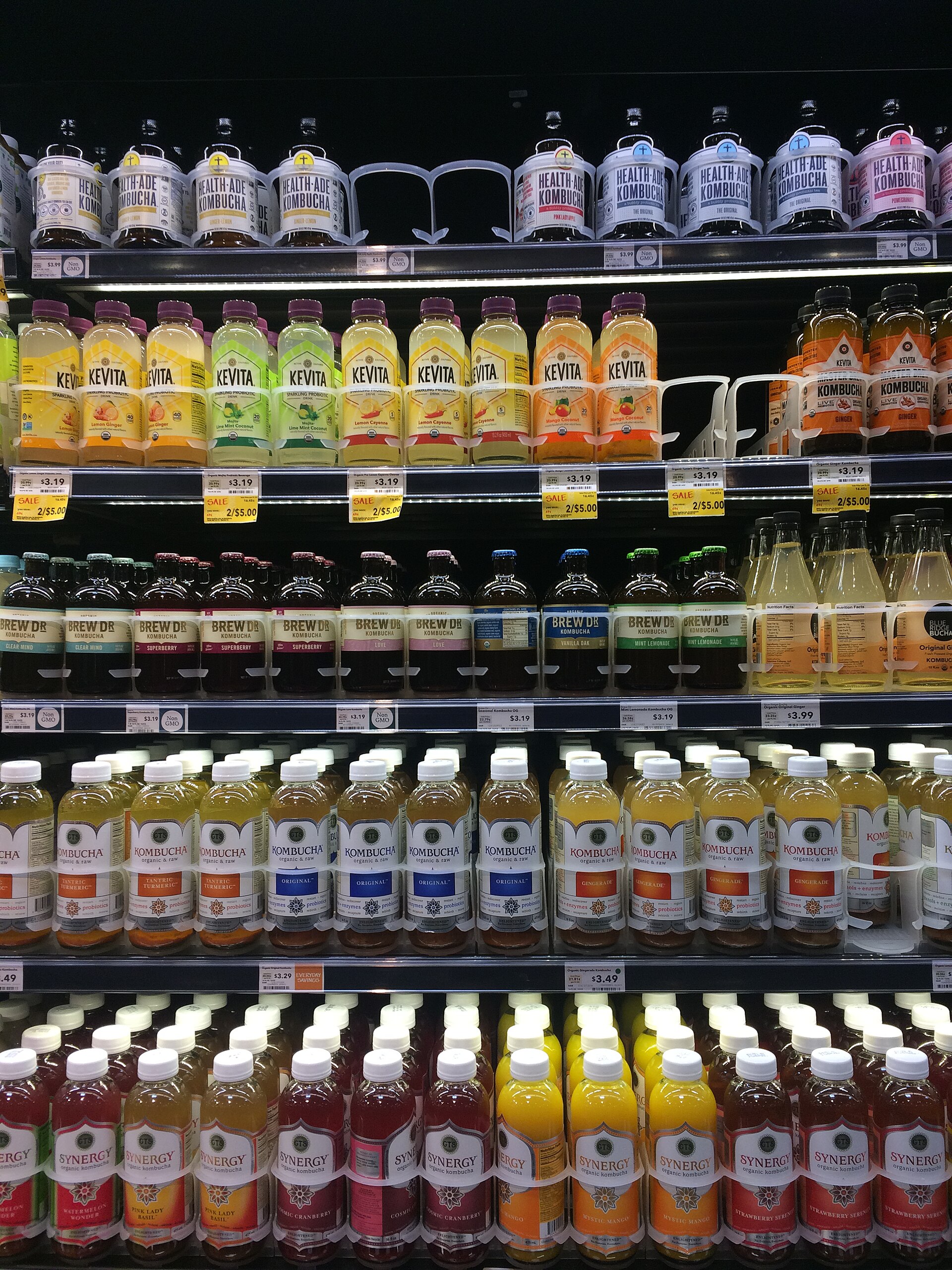Refrigerated store shelves stocked with bottled kombucha and functional drinks from consumer packaged goods brands