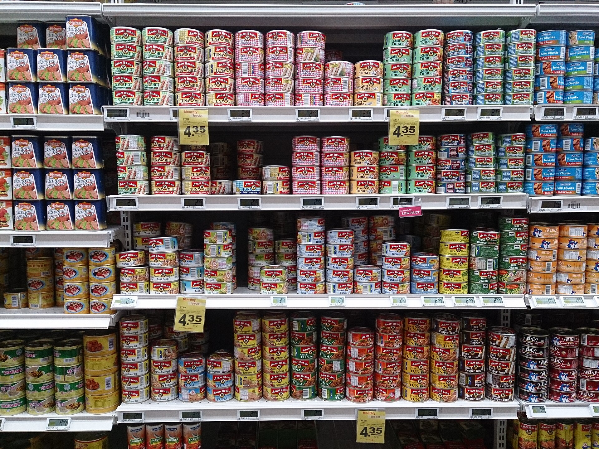 Supermarket shelves stocked with rows of metal food cans, including canned fish