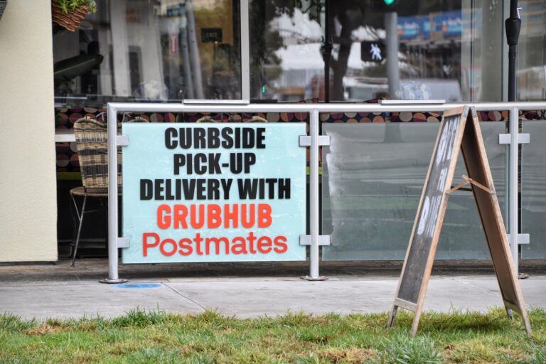 Curbside pick-up and delivery sign for Grubhub and Postmates outside a restaurant